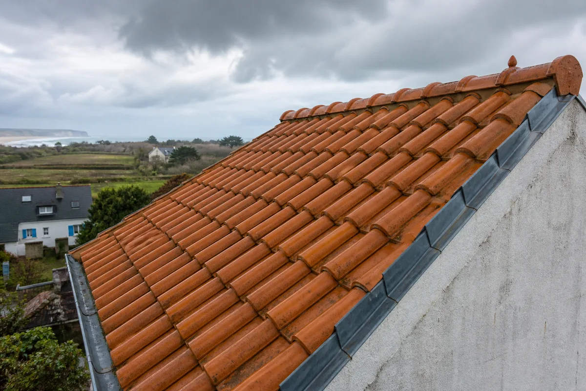 Toiture en tuiles de terre cuite exposée à la pluie et au vent près du littoral